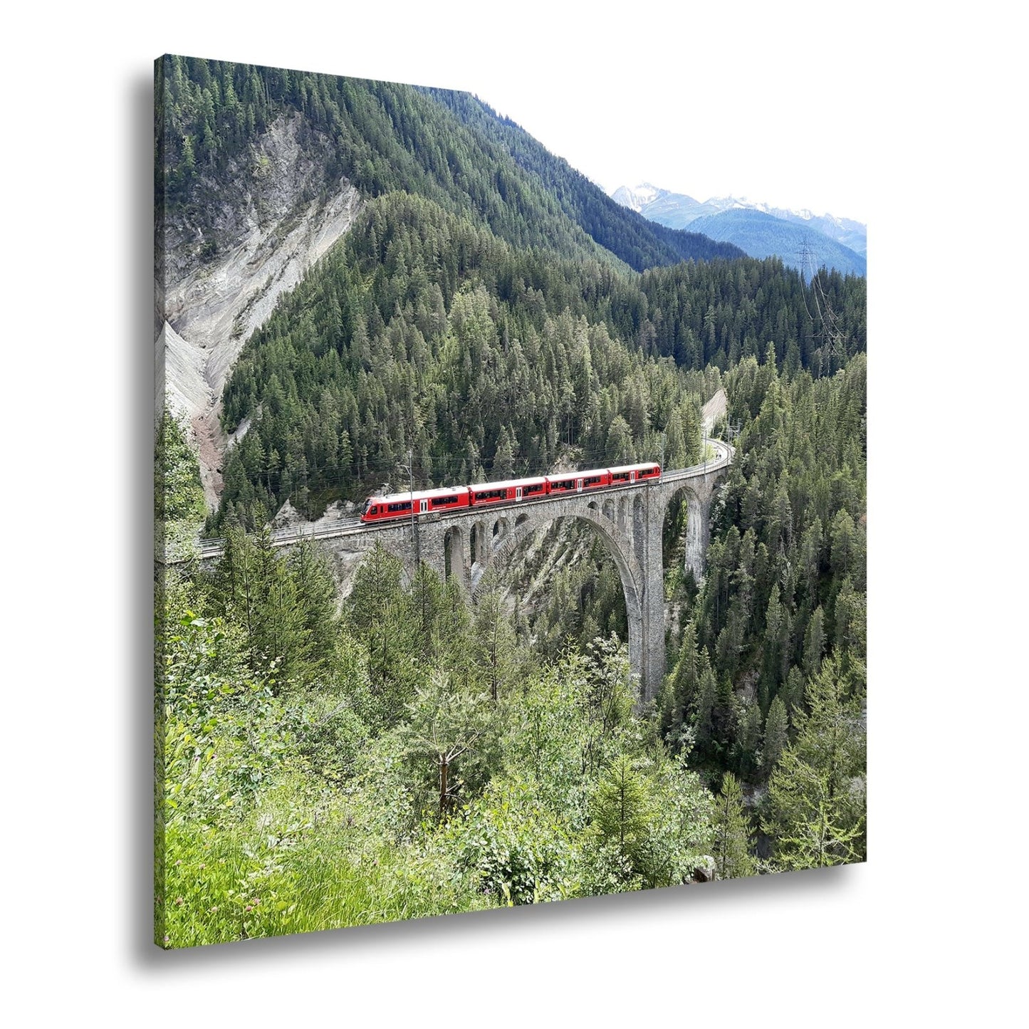 Leinwandbild Ein roter Zug schwebt über ein grünes Meer aus Tannen. - deyoli