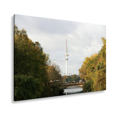 Leinwandbild Hamburg XXL – Goldene Alsterbrücke unter herbstlichen Bäumen mit Funkturm - deyoli
