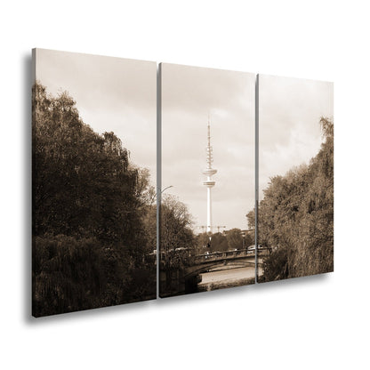 Leinwandbild Hamburg XXL – Goldene Alsterbrücke unter herbstlichen Bäumen mit Funkturm - deyoli