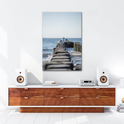 Leinwandbild Möwe trotzt Wellen auf alten Buhnen am ruhigen Meer. - deyoli