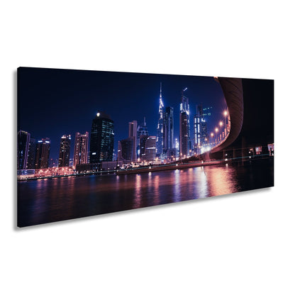 Leinwandbild Skyline XXL – Nächtlich spiegelt in violetten Lichtern - deyoli