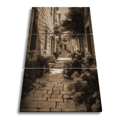 Leinwandbild Verwunschene Gasse voller Blütenpracht und mediterranem Charme - deyoli