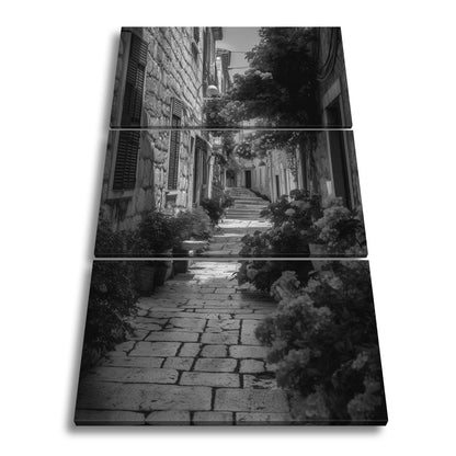 Leinwandbild Verwunschene Gasse voller Blütenpracht und mediterranem Charme - deyoli