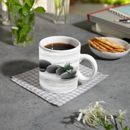 Motivtasse Schwarze Steine, grünes Blatt – Ruhe auf weißem Holz. - deyoli