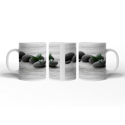 Motivtasse Schwarze Steine, grünes Blatt – Ruhe auf weißem Holz. - deyoli
