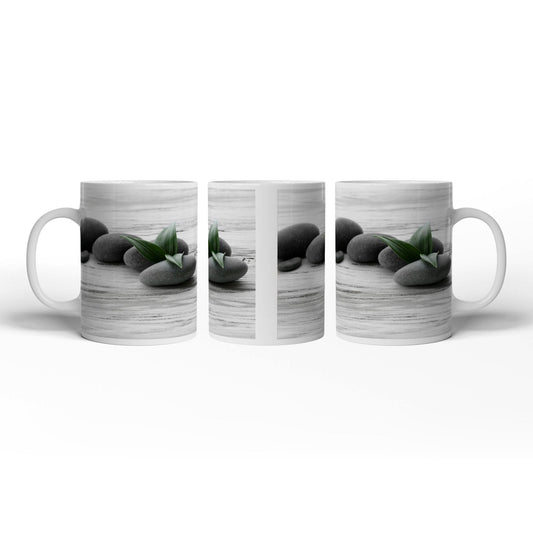 Motivtasse Schwarze Steine, grünes Blatt – Ruhe auf weißem Holz. - deyoli